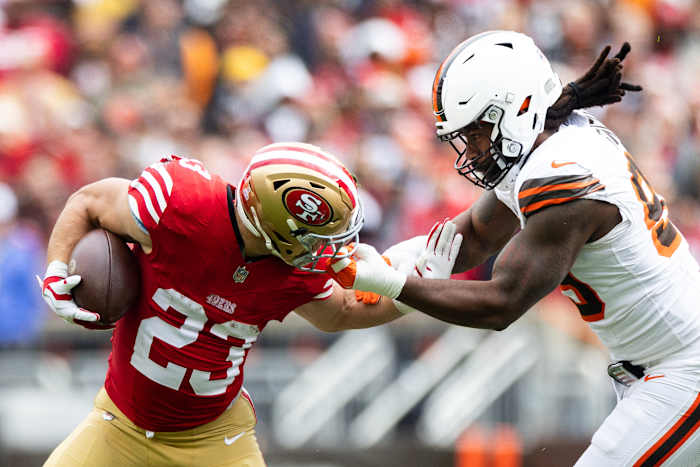 Oct 15, 2023; Cleveland, Ohio, USA; San Francisco 49ers running back Christian McCaffrey (23) runs the ball as Cleveland Browns defensive end Za'Darius Smith (99) grabs him by the face mask during the first quarter at Cleveland Browns Stadium.